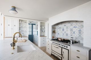 white kitchen with delf tile splashback and brass taps and white range.tif