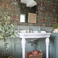 patterned wallpaper and green panelling behind white freestanding sink