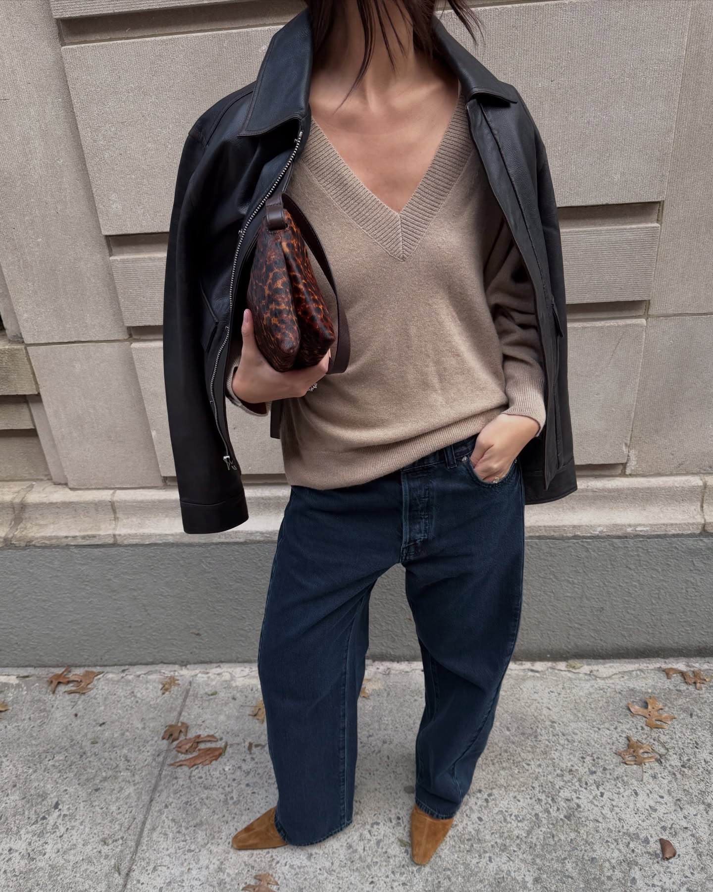 mimixn wears a leather jacket, fine knit v-neck jumper, jeans and ankle boots