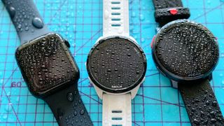 Four smartwatches covered in beads of water.