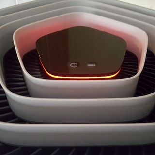 The AEG AX91-604GY Connected Air Purifier seen from above showing a hexagonal filter and LED display panel that's lit up with a red light
