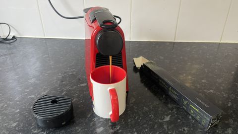 Nespresso Essenza Mini brewing coffee into red and white mug