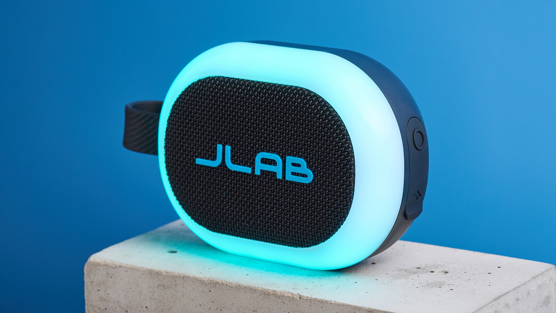 JLab Pop Party portable Bluetooth speaker with RGB lighting photographed on a blue background.