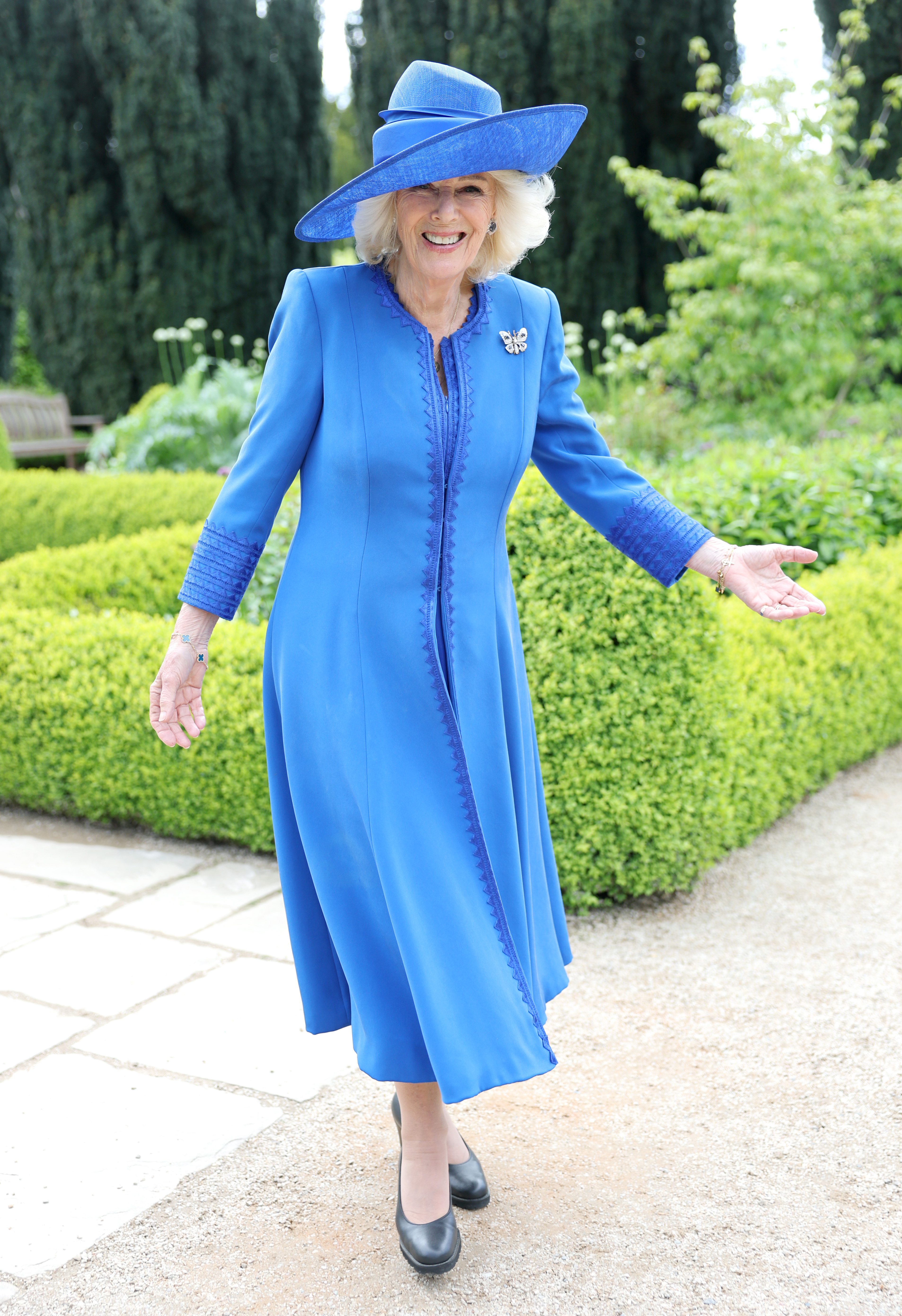 Queen Camilla in a blue coat and hat at a garden party
