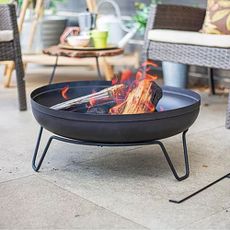 One of the best fire pits filled with burning logs on a paved patio