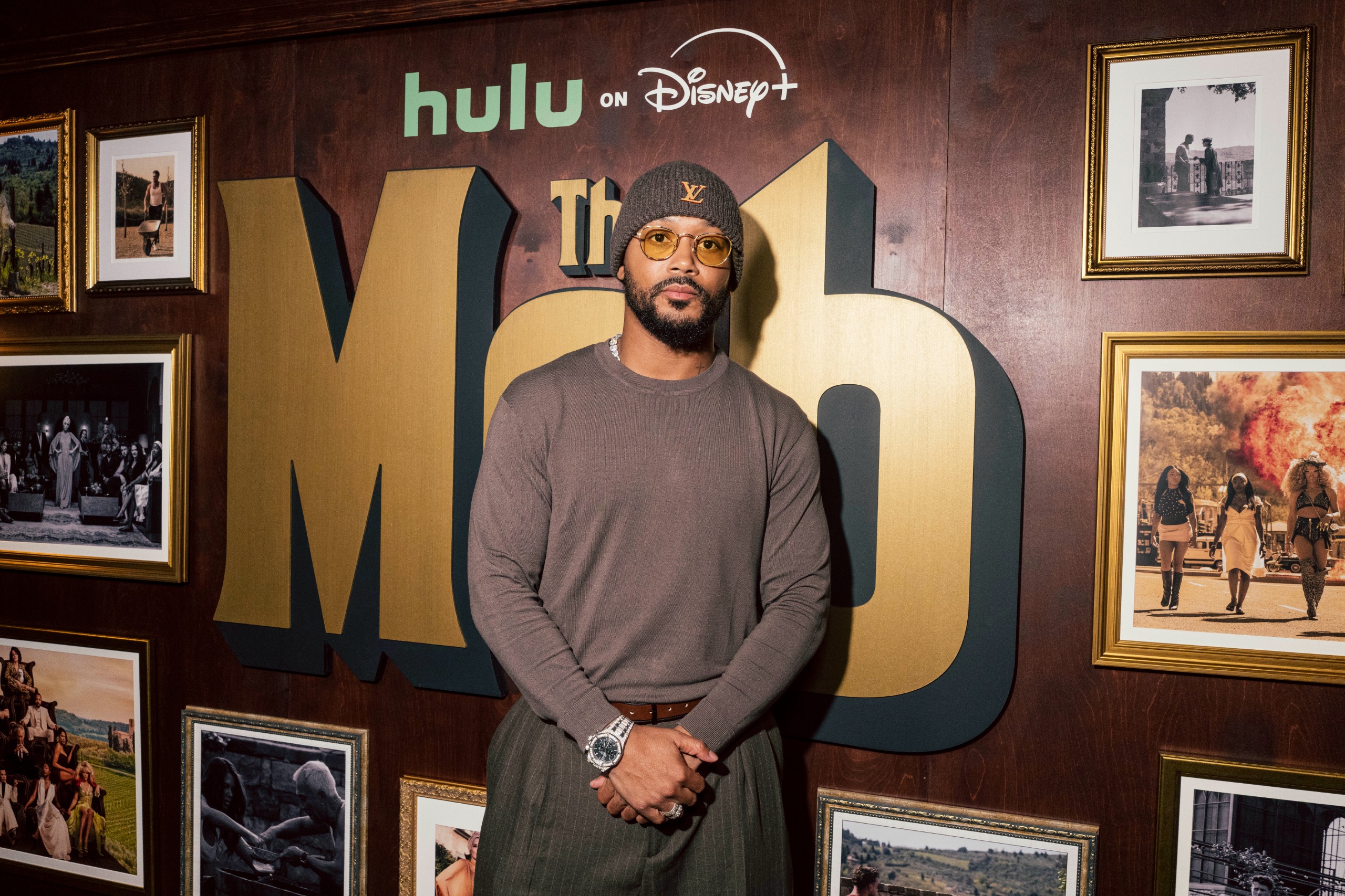 romeo miller wears a brown shirt browsers and a beanie posing at an event for the mob