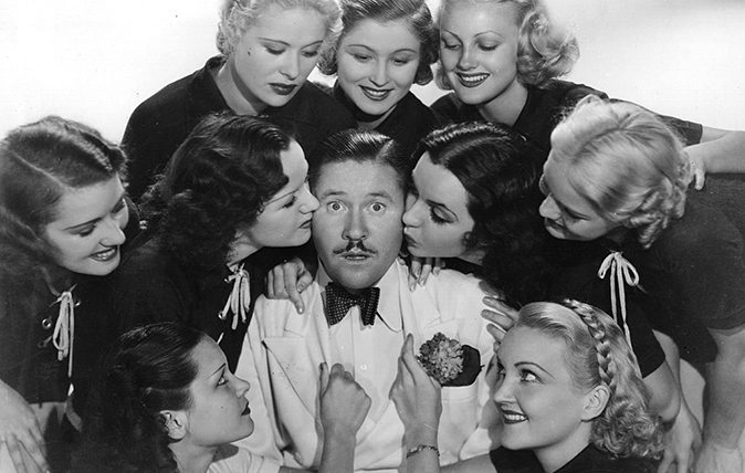 Awkward kissing: Bemused American comic actor Jack Oakie (1903 - 1978) surrounded by a bunch of lovelies in the 1936 Paramount film &#039;Collegiate&#039; (UK Title: &#039;Charm School&#039;), directed by Ralph Murphy.