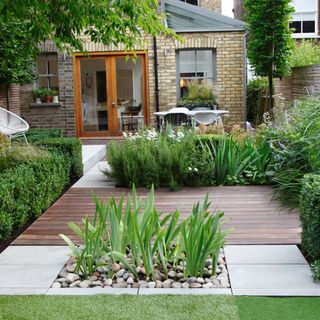 Small garden with structured landscaping to divide the space and a statement water feature