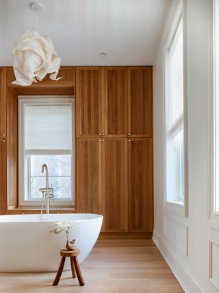 A white tub surrounded by warm wooden cabinets