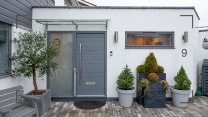 white and blue house exterior with potted plants