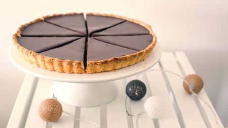 sliced chocolate tart on white pie dish sitting on white table