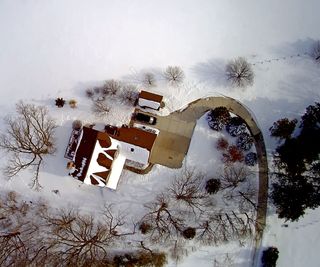 An aerial view of a home in the snow with a clear driveway