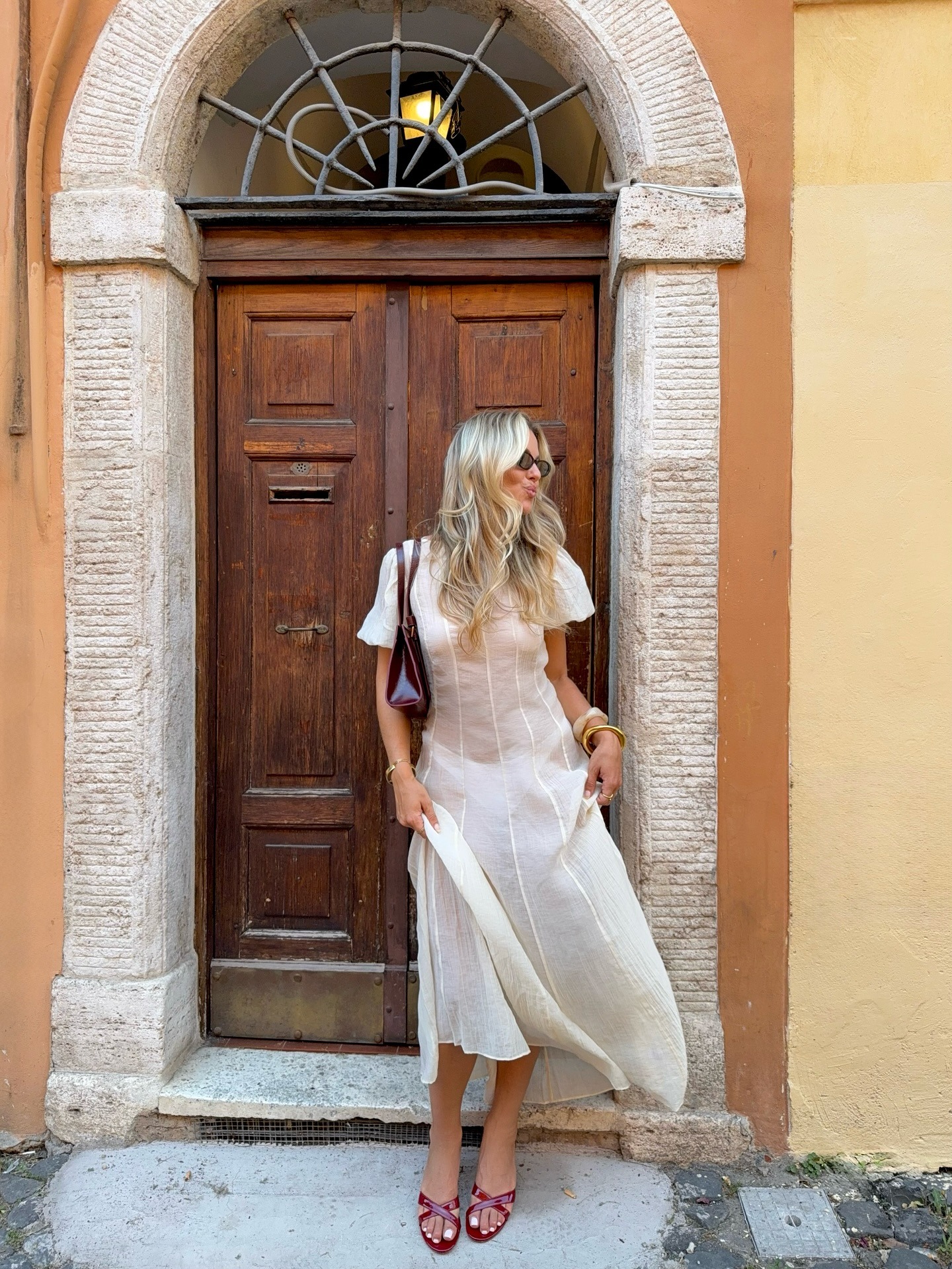 A woman standing in front of a door with wavy hair.