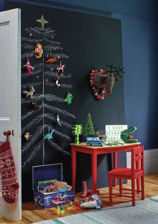 A child's bedroom or playroom with chalkboard wall decor with tree drawn in white chalk and decorations fixed to wall
