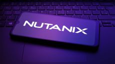 Nutanix logo pictured on a smartphone screen placed on top of a desktop computer keyboard.