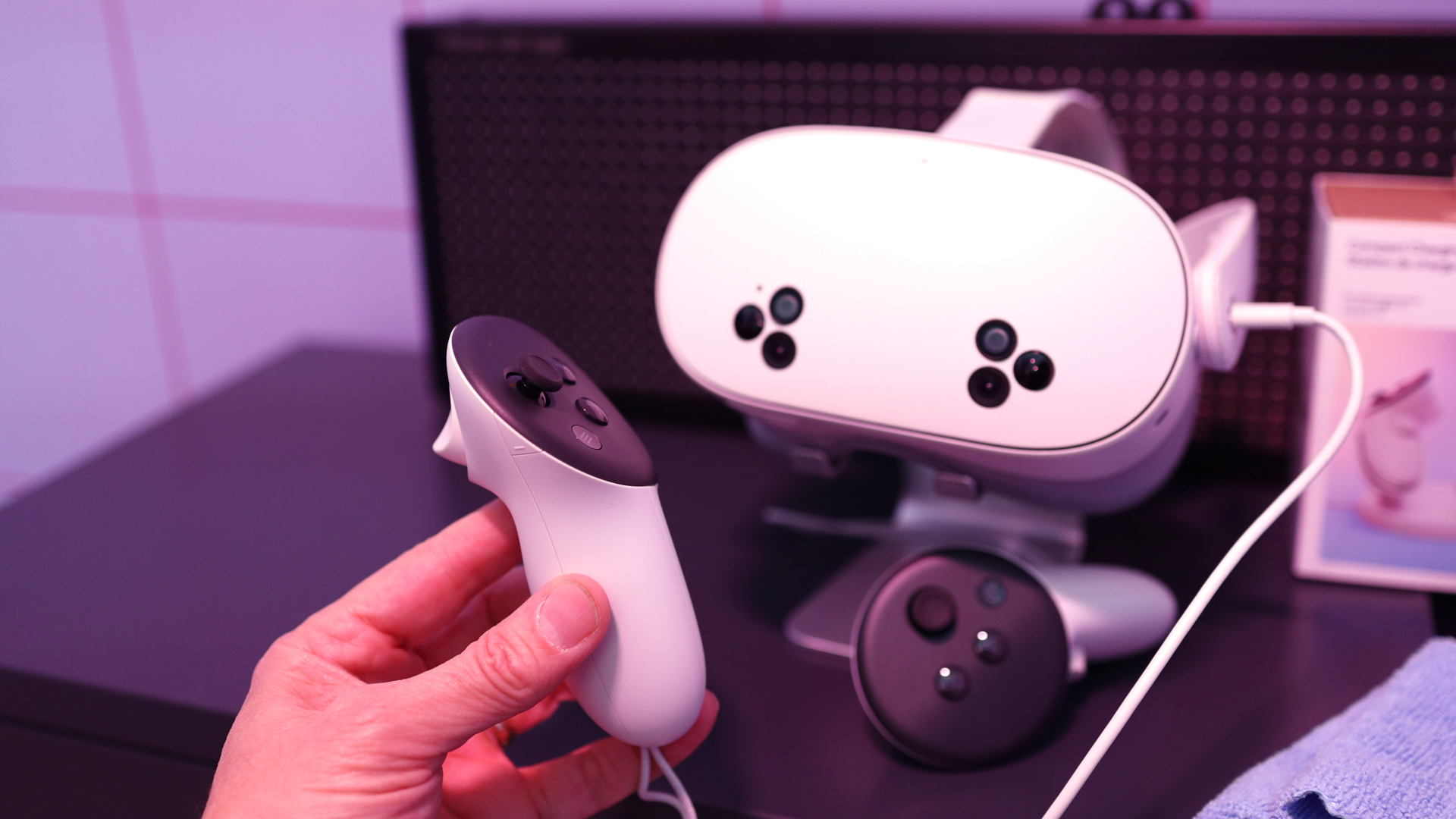 Meta Quest 3S controller being held up in front of the headset on a stand