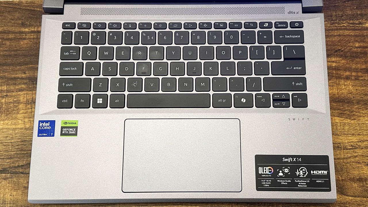 Overhead of the Acer Swift X 14's keyboard and touchpad against a wooden table.