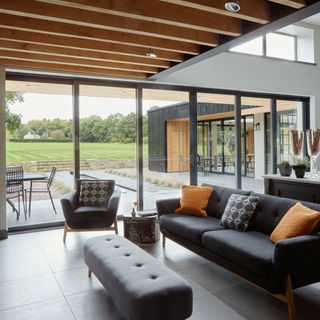 Living room in extended barn with swathes of glass doors and clerestory windows