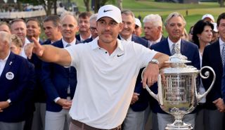 Koepka points whilst posing next to the trophy