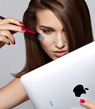 Woman Using iPad Screen to See Whilst Putting on Makeup