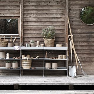 galvanised storage units with garden pots, plants, baskets, garden tools, bulbs, string, on decked area at the side of a house