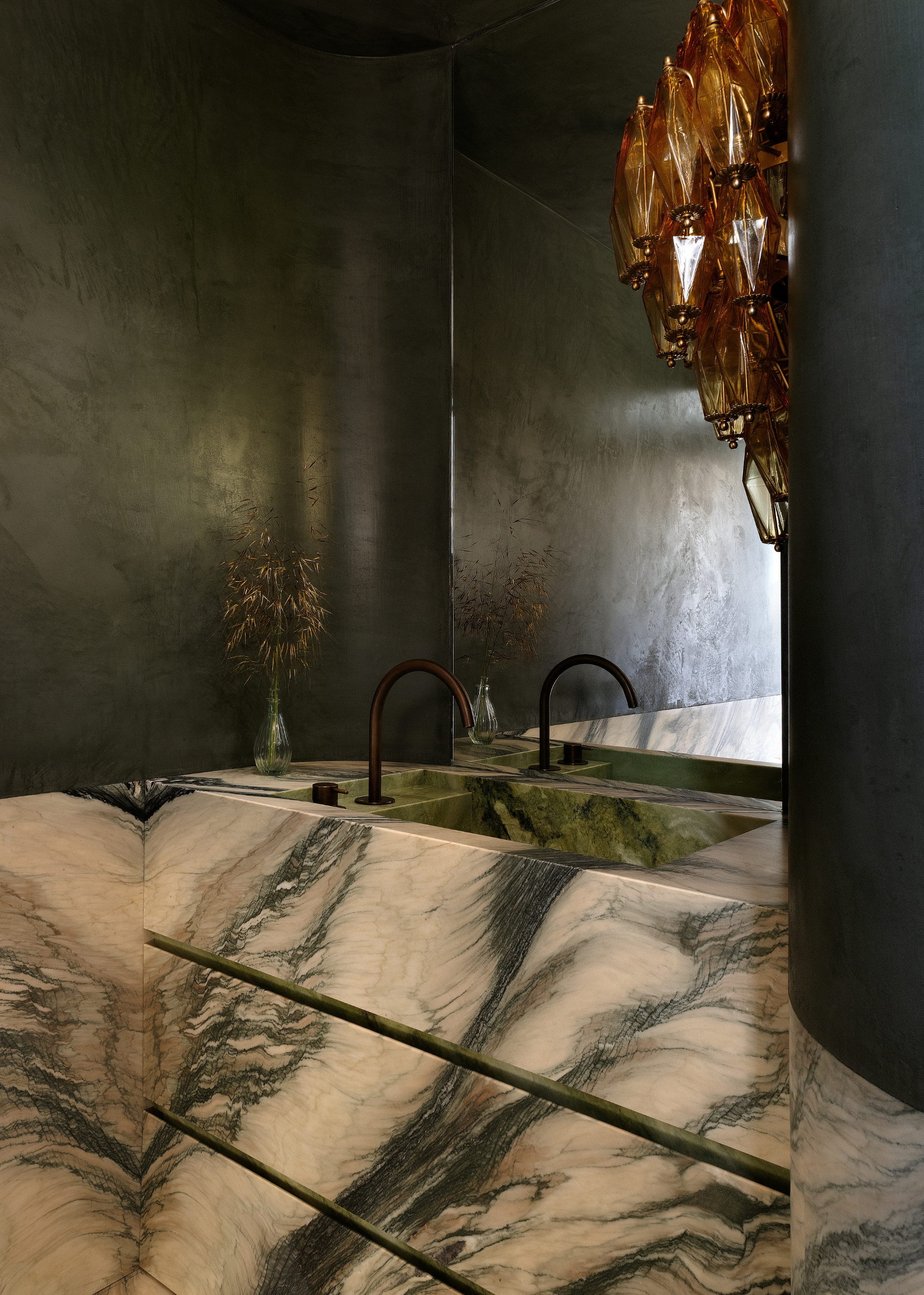 a beautiful marble sink in a dark green cavernous bathroom