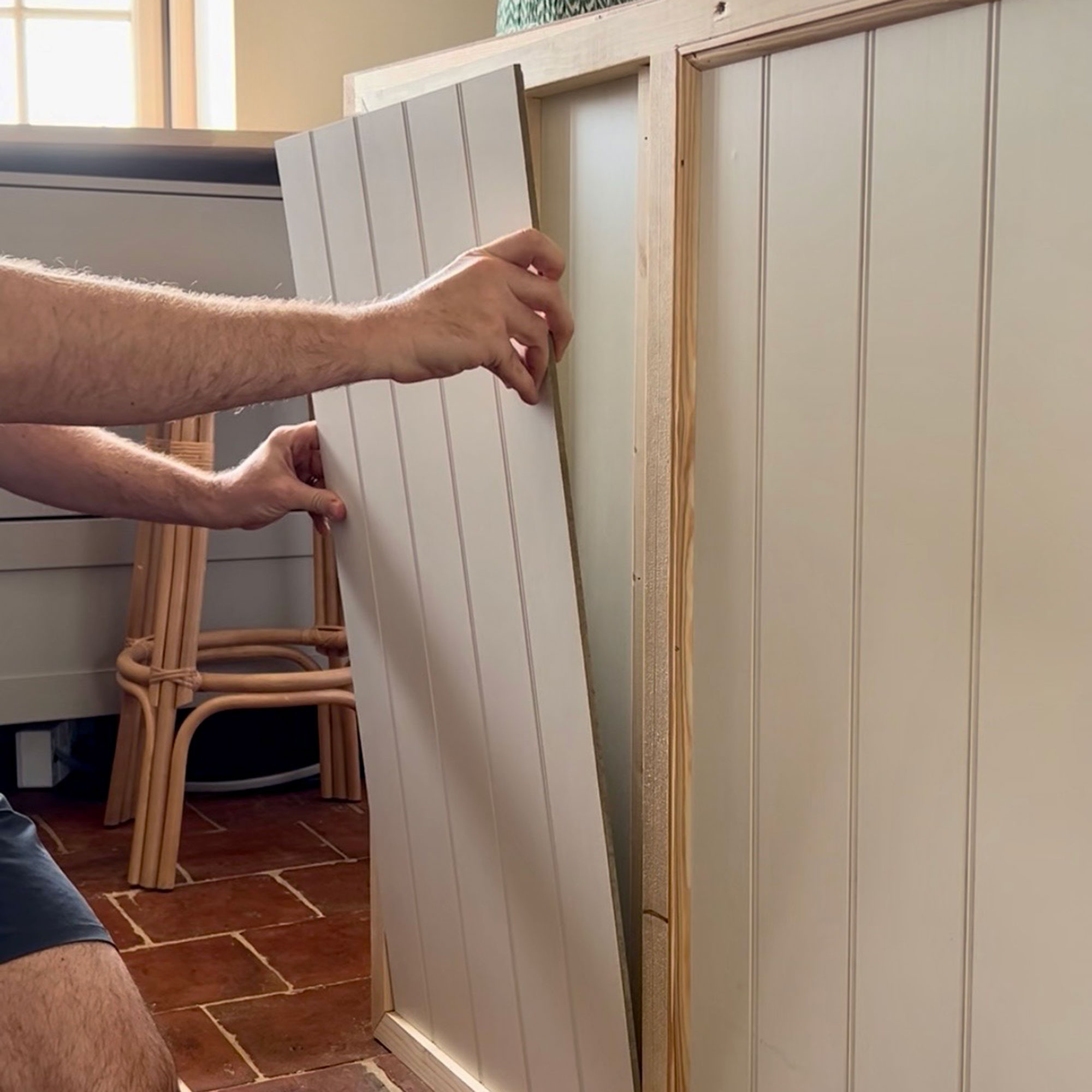 Man placing panelling onto island in kitchen