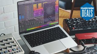 A home studio setup with laptop, audio interface, synthesizers, MIDI keyboard, and studio headphones