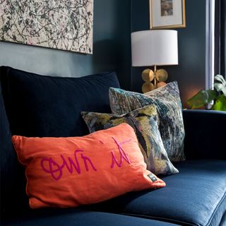 blue living room with blue sofa and orange cushion