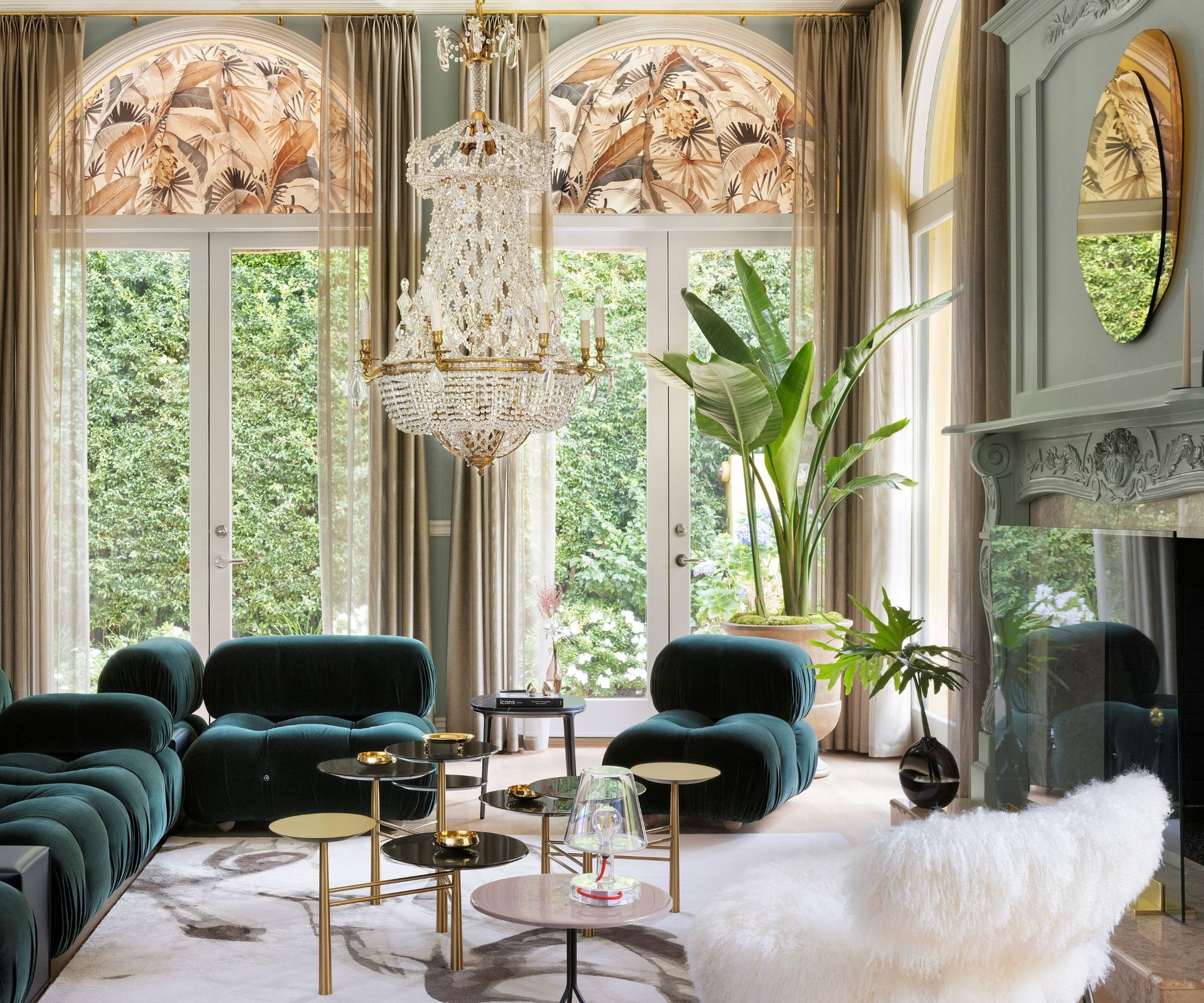 living room with green sectional and white fluffy chair and arched windows