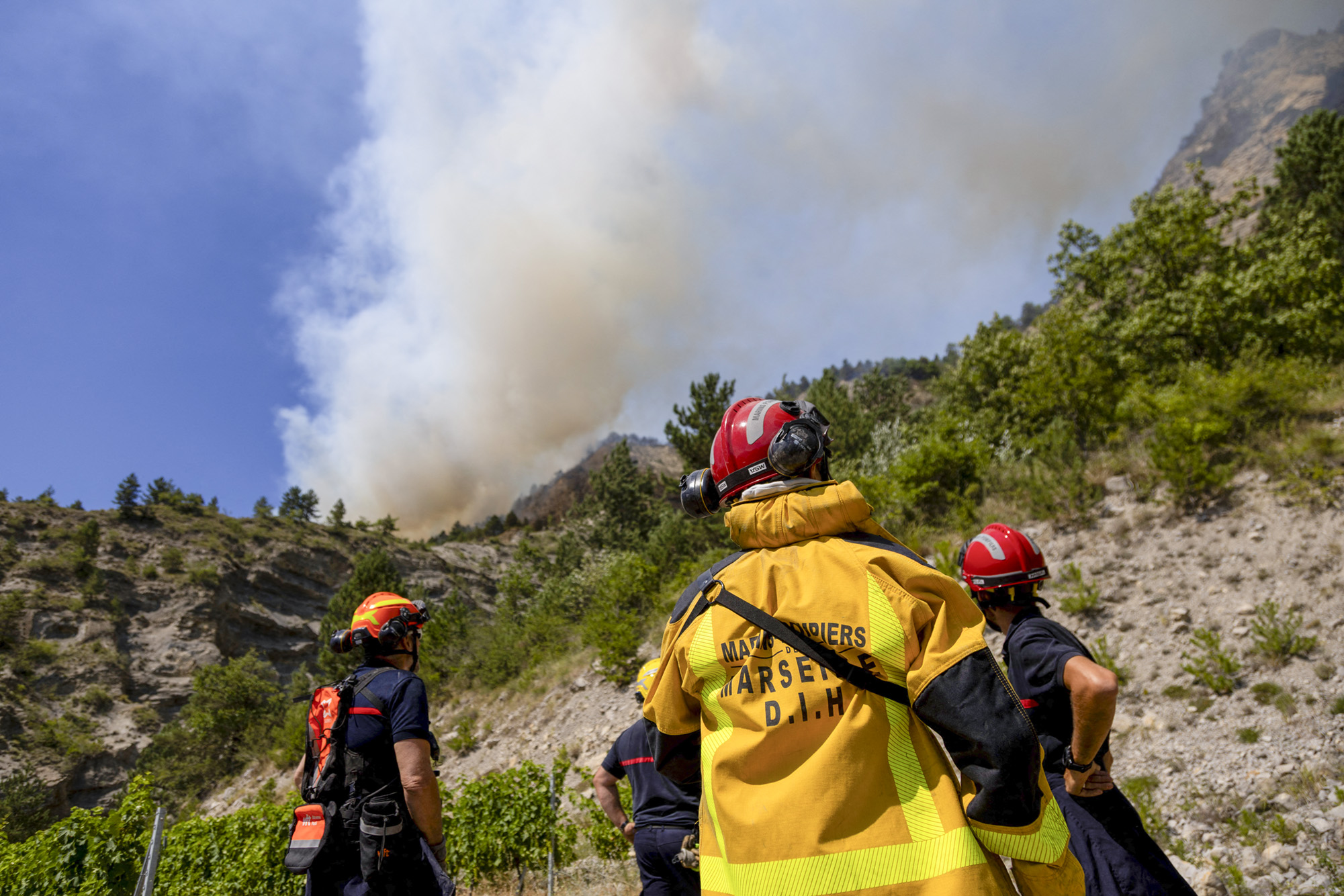 A huge plume of smoke rises from the wildfire just above a team of firefighters monitoring its progress. France, Drome, Aurel, July 8, 2026. A wildfire is currently burning in the Drome region, where it is dangerously approaching the village of Aurel. (Photo by Thibaut Durand / Hans Lucas / AFP via Getty Images)
