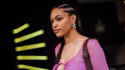 woman in a purple sweater with braids walking into the sun