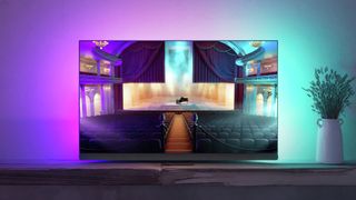 Philips OLED908 montrant une scène de concert, sur un banc TV, dans un salon