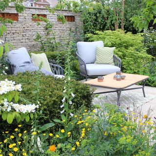 A set of garden chairs surrounded by lush foliage and flowers at RHS Chelsea Flower Show