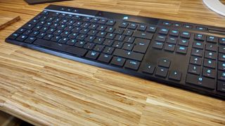 A black Corsair K100 Air Wireless keyboard on a wooden table
