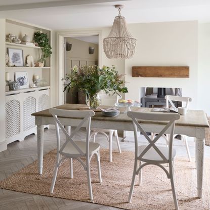 Dining area in a barn conversion with white wooden table and chairs and a beaded chandelier