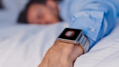 Man sleeps on bed wearing a fitness tracker
