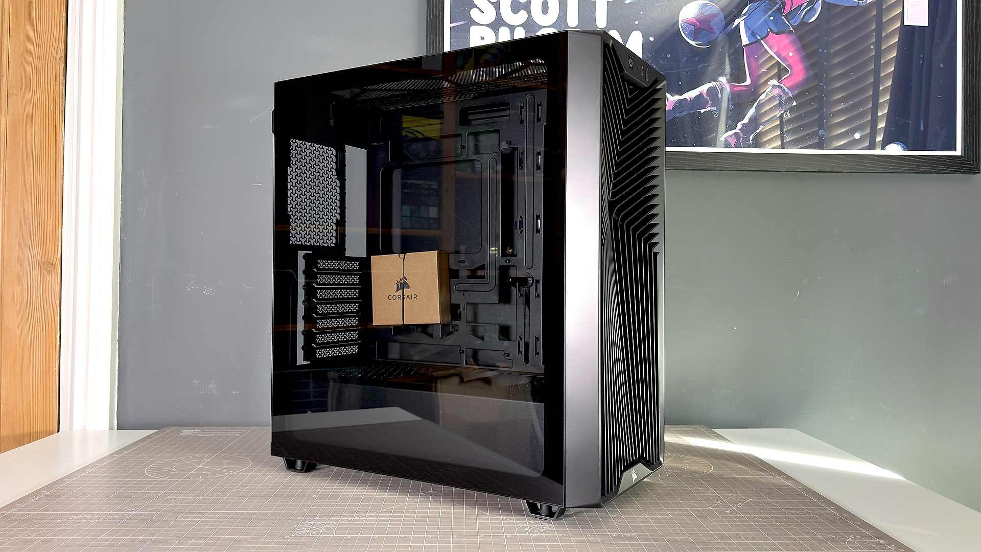 A Corsair PC case, the 3200D, on a desk with various panels removed and ready for a PC build.