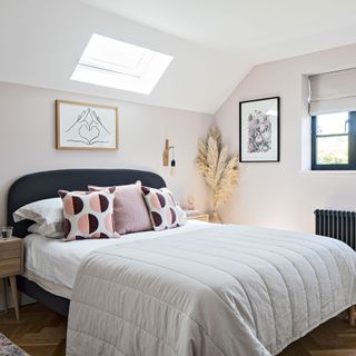 Main bedroom in attic space with pale pink walls and roof light in ceiling