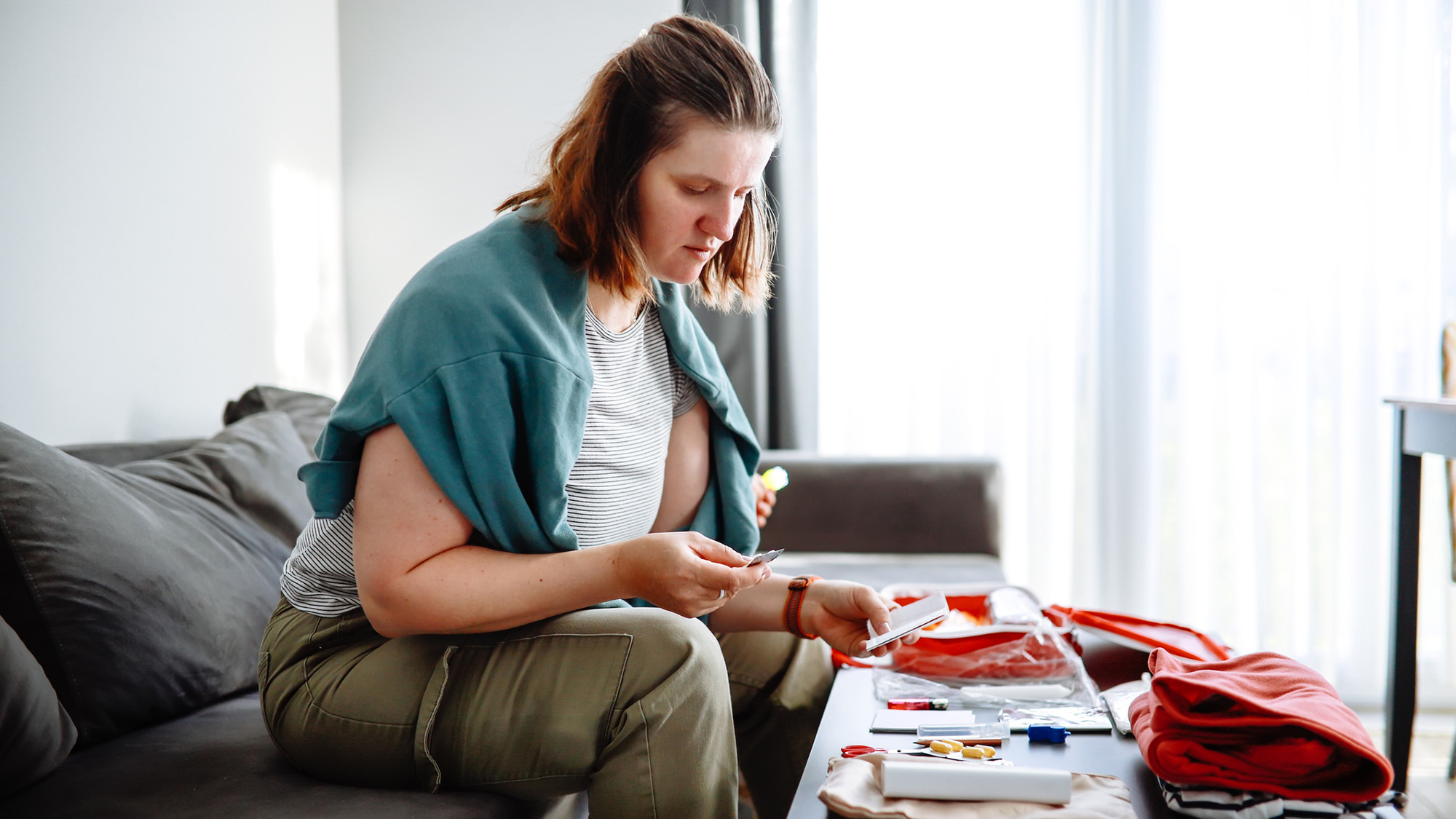A woman with short brown hair sits over a coffee table full of first-aid supplies