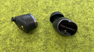 Bowers & Wilkins Pi8 earpieces on a green background