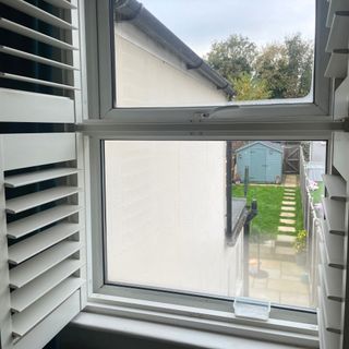 Window looking out onto a garden with a pot of baking soda on the windowsill