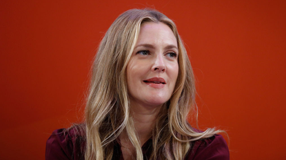 Drew Barrymore smiles against a red background