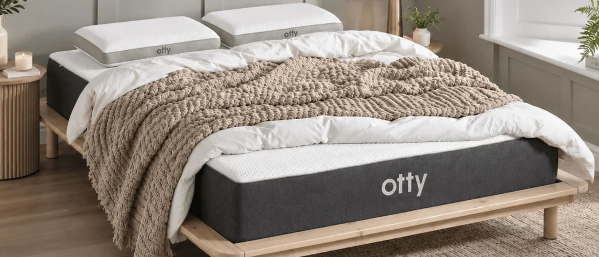 The charcoal and white Otty Original Ice Hybrid Mattress on a wooden bedframe, set within a neutrally decorated bedroom