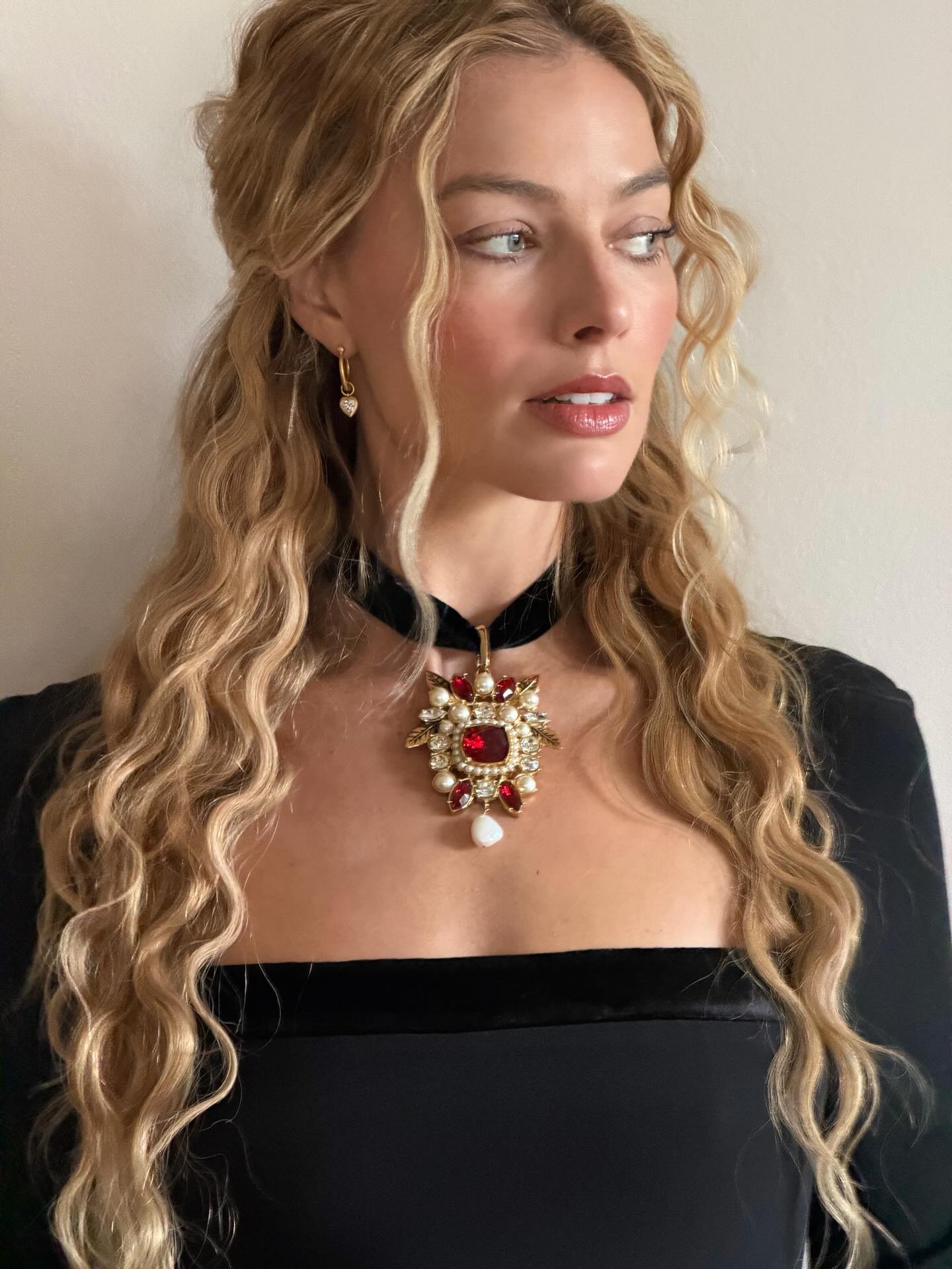 Margot Robbie with wavy tendrils, looking off camera