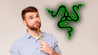 A bearded man holding a pencil to his chin and looking thoughtfully at a large Razer logo.