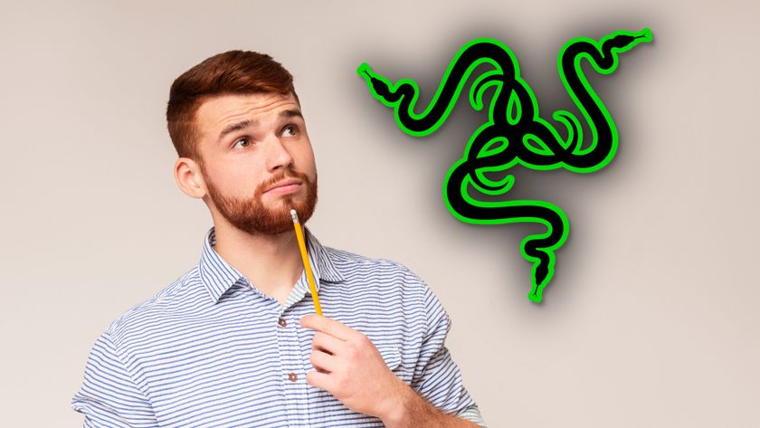 A bearded man holding a pencil to his chin and looking thoughtfully at a large Razer logo.