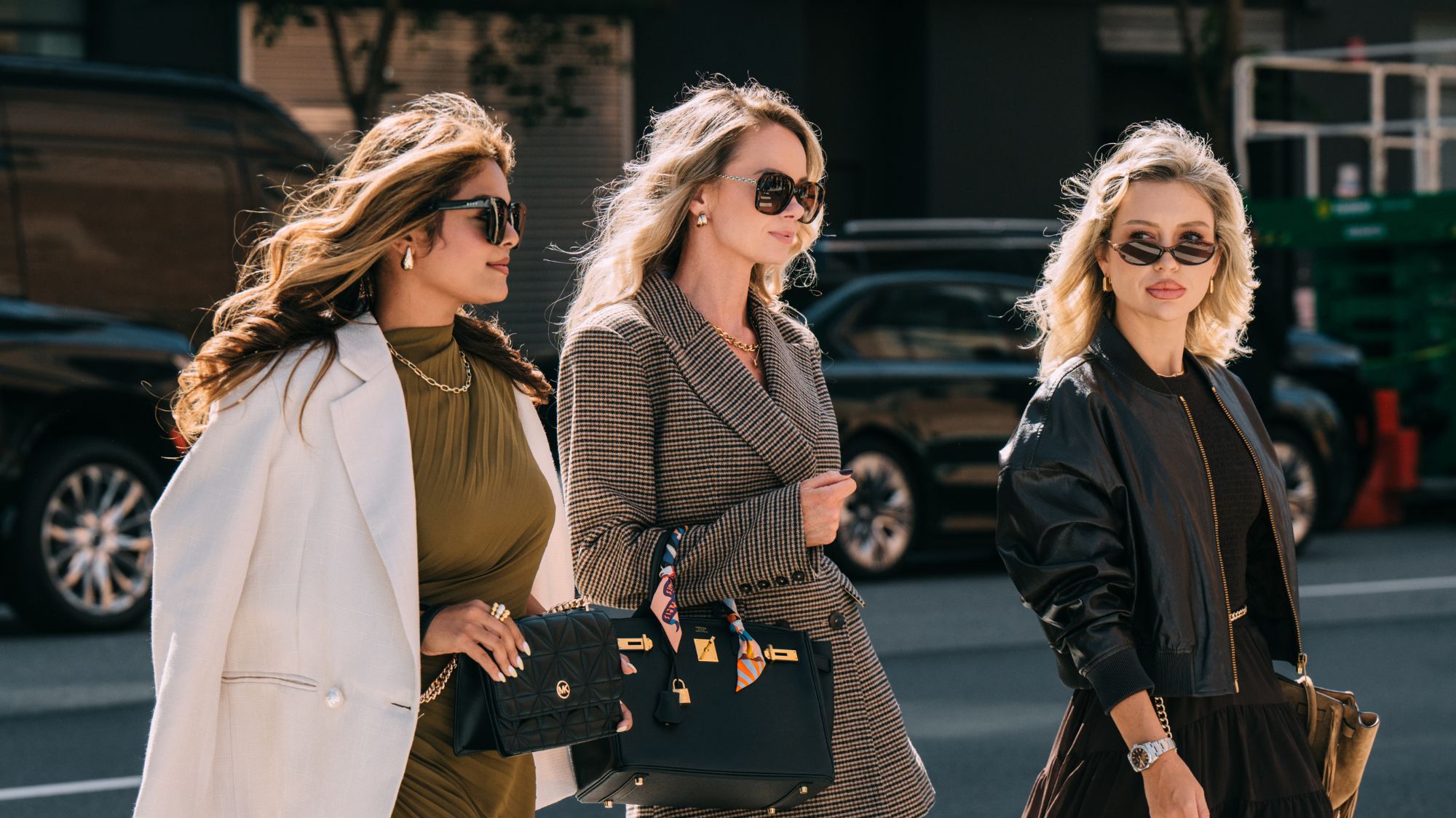 three women walking down the street wearing sunglasses with big bouncy blowdries