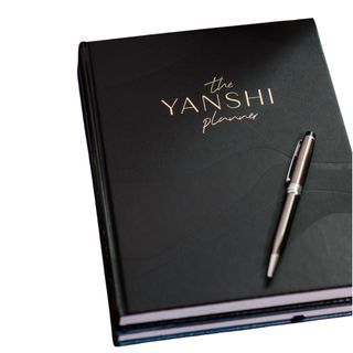 A black budget planner with gold text and a black and silver pen resting on top