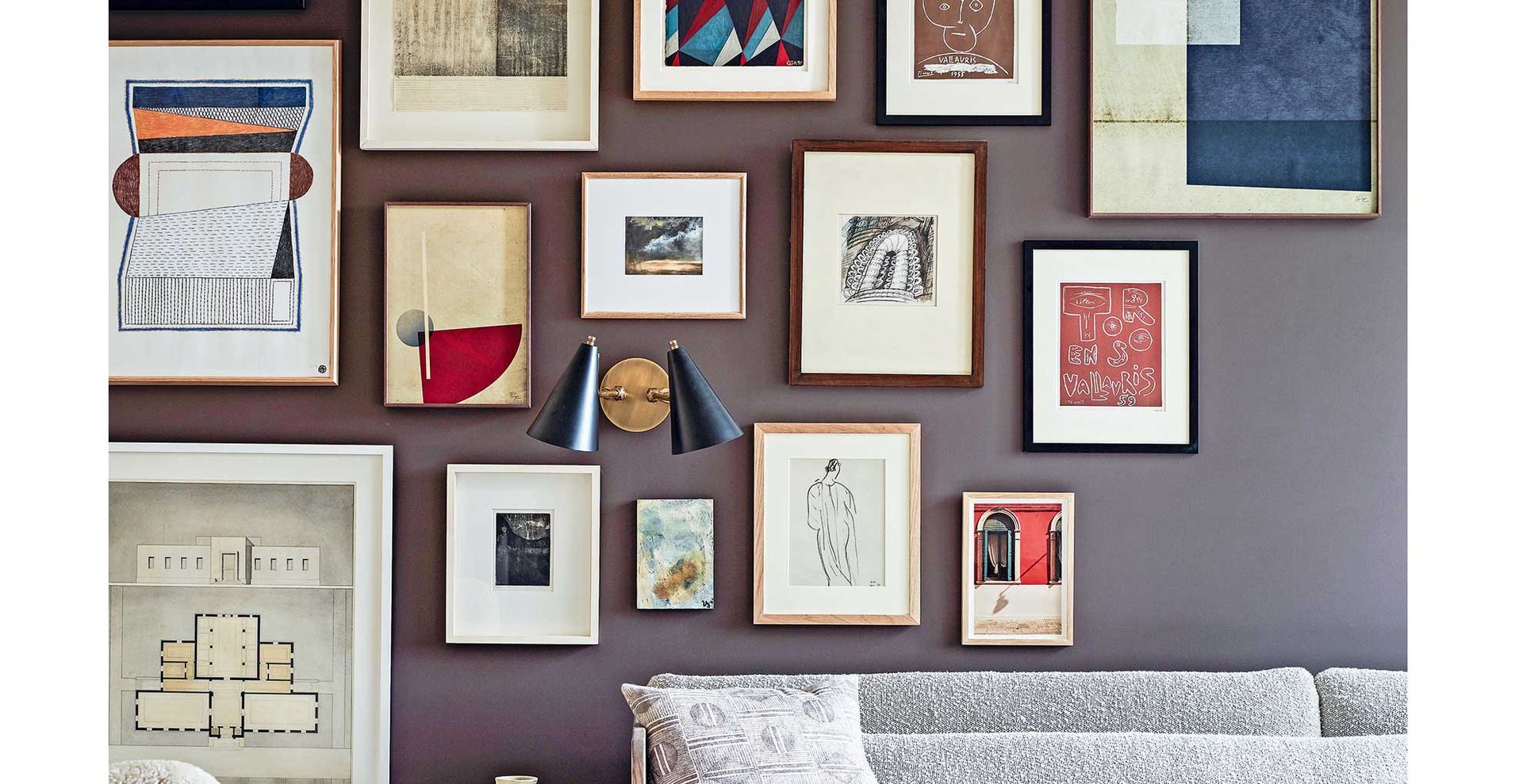 Navy blue living room wall with lots of framed artwork to show how to make a home feel cosy